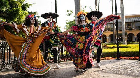 People in traditional outfits and face paint dancing and celebrating the day of the dead.