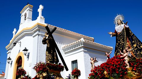 Sculpture of the Virgin Mary next to a church.