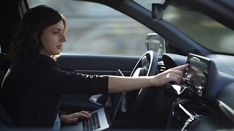 Businesswoman with laptop using navigation device in driverless car.