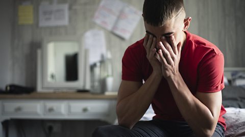 Stressed teen sat with his head in his hands.