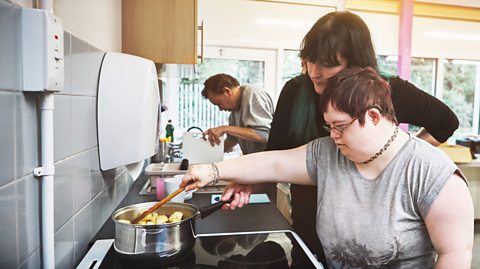 Mother and child with down syndrome cooking in the kitchen.