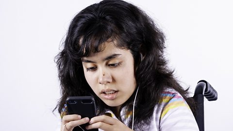 Girl in wheelchair listening to music on phone.