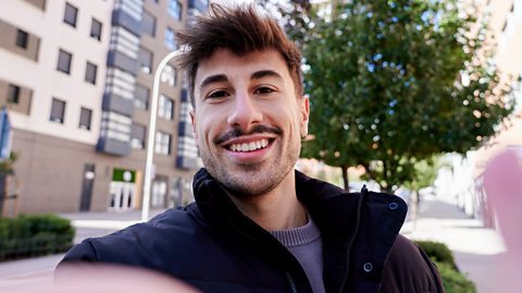 Man smiling while taking a selfie outdoors.