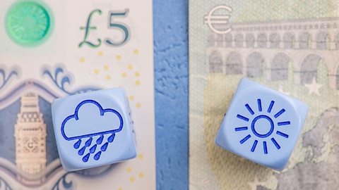 Two dice with weather symbols on them sitting on a five pound note and a five euro note