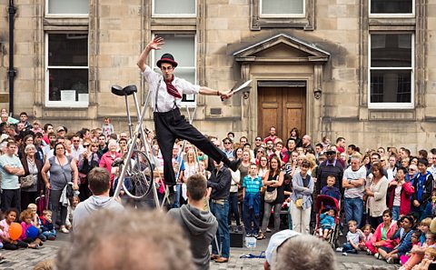 An Edinburgh Fringe street performer performing a trick of balancing on a tightrope