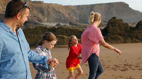 A young family all walking together on a beach in the afternoon on a home education trip