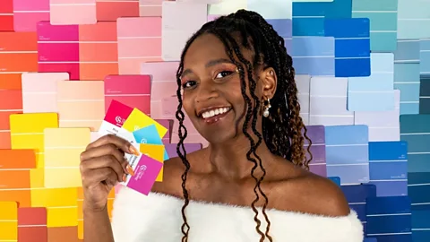 Micah Lumsden Micah Lumsden holding up colour swatches against a background of various bright colours