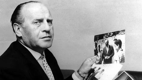 Alamy Oskar Schindler holds up a photograph of him with people (Credit: Alamy)