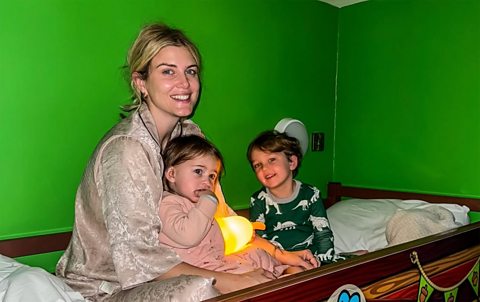 Ashley, Alfie and Ada smiling for a picture together in bed.