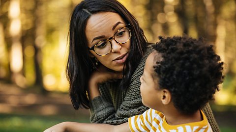A mother talking to her young child outdoors to build their communication life skills
