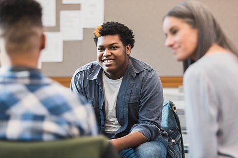 Three smiling teenagers in a room discuss the life skills of empathy and diversity