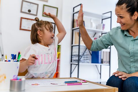 A home education art class, parent and small girl with Down syndrome giving high-five