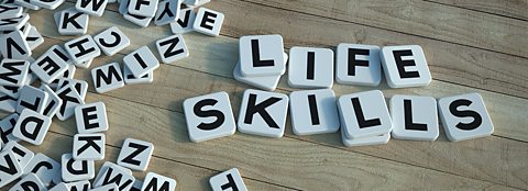 White tiles with letters spelling out: LIFE SKILLS, on a wooden surface