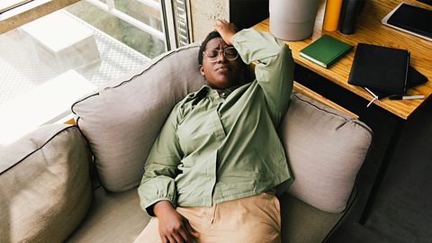 Woman laying down on sofa with headache.