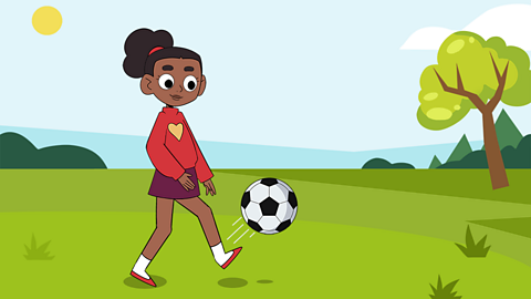 A young girl kicking a football in a park