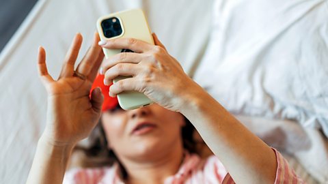 Female laying in bed and looking at her phone