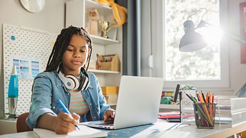 Student on a desk completing homework on a laptop.