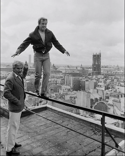 Getty Images Belmondo, pictured with his brother Alain, testing his balance on the set of another of his action films, 1983's Le Marginal (Credit: Getty Images)