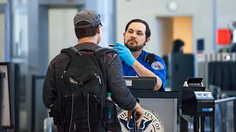 Alamy A man stops to be checked by a security guard at an airport terminal (Credit: Alamy)