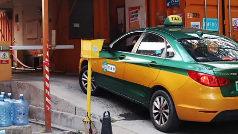 Iris Liu A green and yellow electric taxi in Beijing entering a battery swap station (Credit: Iris Liu)
