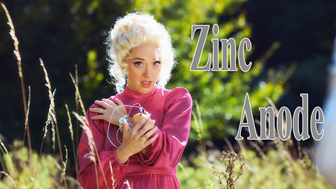 A woman with a red dress and blonde hair wearing a potato around her wrist with wires coming from it.