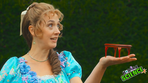 An still photograph from the clip of a lady holding a small table.