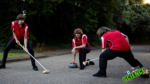 A still photograph of a group of men trying to play curling on a road.