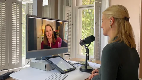 BBC BBC Special Correspondent Katty Kay speaks to author Gretchen Rubin on a video call. Kay is shown from behind with white earbuds and a black microphone and she wears a green shirt. Rubin is shown on her monitor and can be seen wearing a dark red shirt and black earbuds (Credit: BBC)