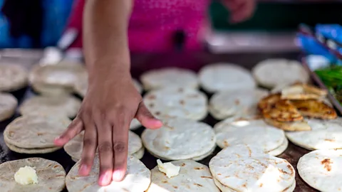 Getty Images A person makes pupusas on a grill (Credit: Getty Images)
