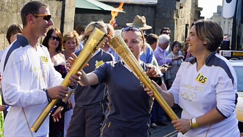 Two olympic torch bearers in 2012 exchanging the flame