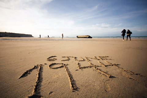 The words 6 June 1944 written in sand on a beach in Normandy