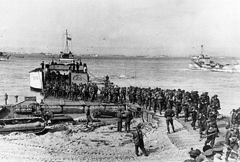 Soldiers land at a beach on a small boat in Normandy in 1944
