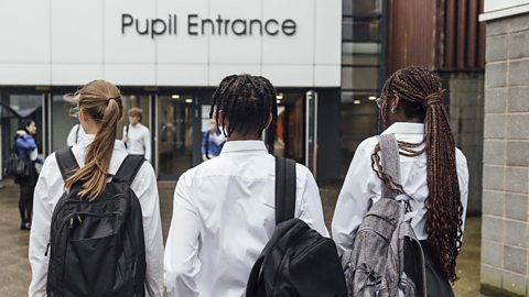 Pupils walking with their backs to the camera into school through the pupil entrance