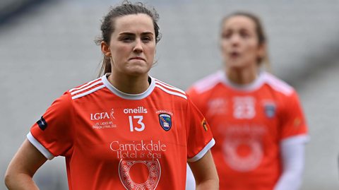 Two Antrim GAA fadies football team members with a local business sponsor's logo on their jerseys - playing in a league sponsored by LIDL, a major supermarket in Northern Ireland.