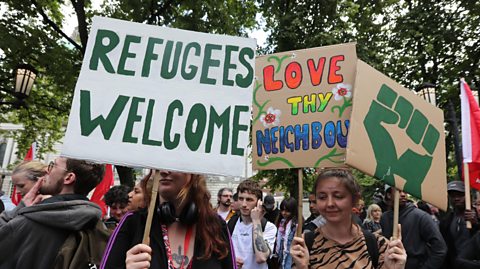 Young people holding aloft banners at the anti-racism march in Belfast - the banners say 'Refugees welcome' and 'Love thy neighbour'