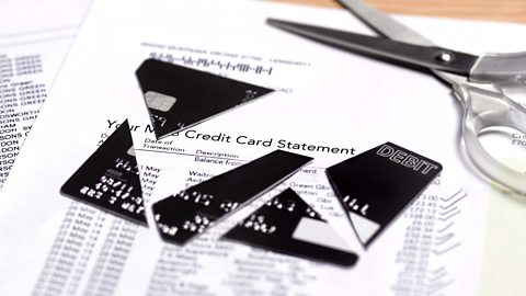 A credit card statement with scissors and a cut up debit/credit card on top.