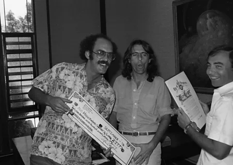 Getty Images In 1978, Alice Cooper (centre) and his manager Shep Gordon (left) presented a cheque to sponsor one of the letter Os in the Hollywood sign (Credit: Getty Images)