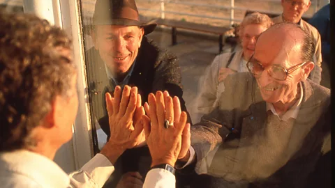 Global Ecotechnics Corporation John Allen, Biosphere 2 founder (in hat), exchanges a biospherian handshake with Mark Nelson, on near side of the glass (Credit: Global Ecotechnics Corporation)