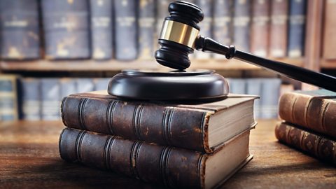A judge's gavel placed ontop of two stacked legal books.
