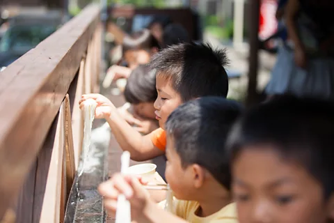 Alamy Nagashi somen is a ritual where children and adults try to catch cold noodles flowing down bamboo chutes (Credit: Alamy)