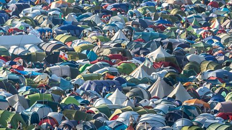 Aerial view of a packed festival campsite with colorful tents and people gathering at a music event