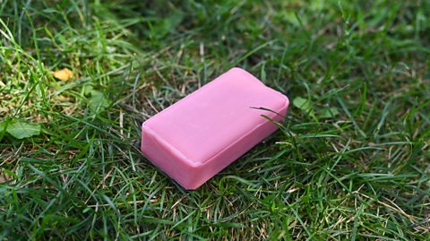 Pink bar of soap resting on green grass, representing eco-friendly hygiene and outdoor cleanliness