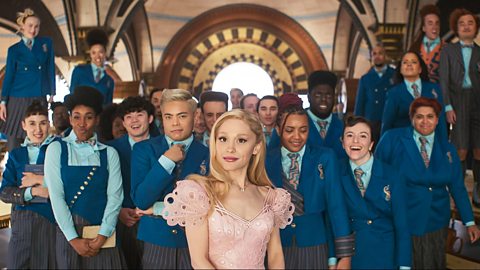 Ariana Grade dressed in pink as Glinda in a class photo in the movie Wicked