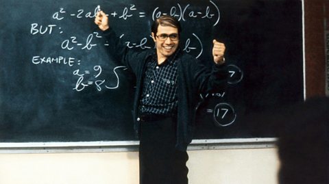 1980s movie Stand and Deliver with a happy teacher pointing to the blackboard smiling at his students