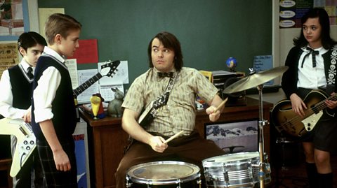 Jack Black playing the drums in a classroom in the School of Rock movie