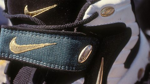 Two gold Nike swoosh logos visible on this close up of a black and white trainer