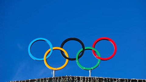 The five Olympic rings: blue, yellow, black, green and red displayed against a deep blue sky