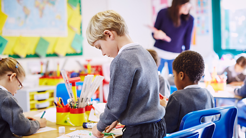 A classroom of young kids in uniform play arts and crafts.