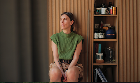 Milda Mitkutė, the founder of Vinted sits next to some items on a shelving unit