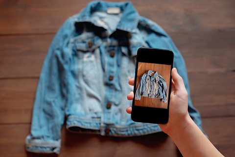 An old denim jacket is being photographed on a mobile phone
